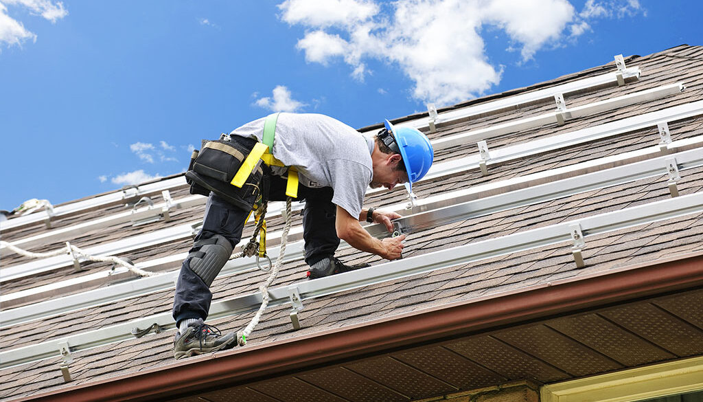 A Man Standing on a Roof Installing Solar Panel Rails Rust on Solar Mounting Systems