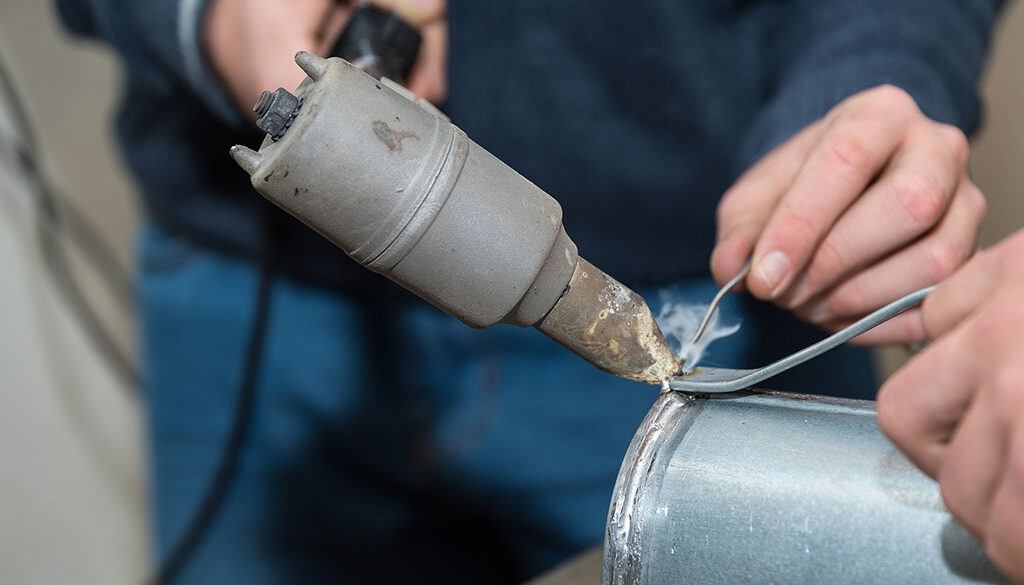 Closeup Of A Man Using A Soldering Iron On Galvanized Steel Can You Solder Galvanized Steel