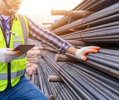 A Worker Holding His Hand On A Bundle Of Ground Rods During The Galvanized Steel Inspection Process
